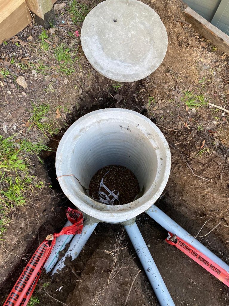 Open 18 inches underground concrete pull box and pipes in trench