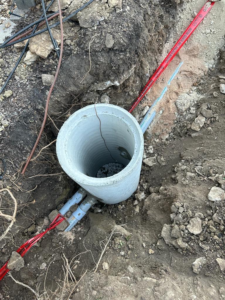 Open concrete pull box with underground pipes at construction site