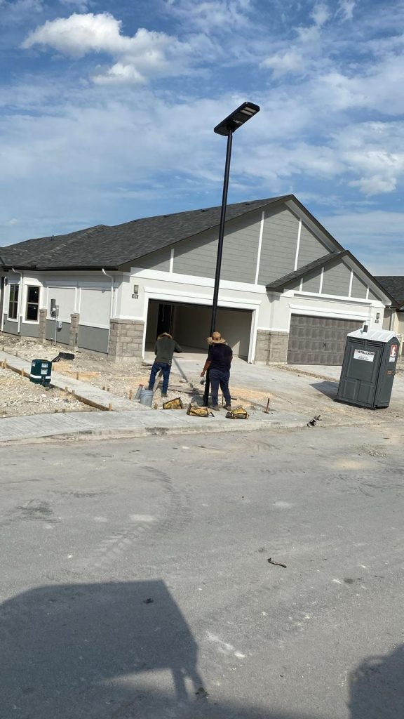 Two construction workers finishing the installation of a temporary solar street light pole.
