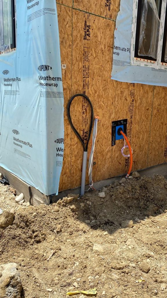 New house under construction with electrical conduit, wiring and a blue electrical box visible.