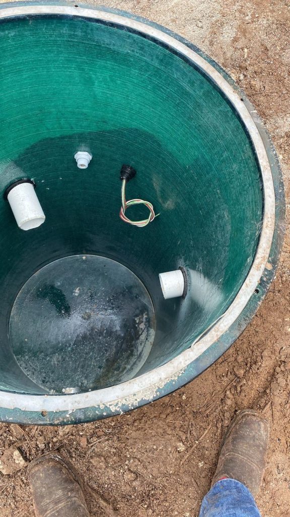 Green underground tank installation with pipes and electrical connections