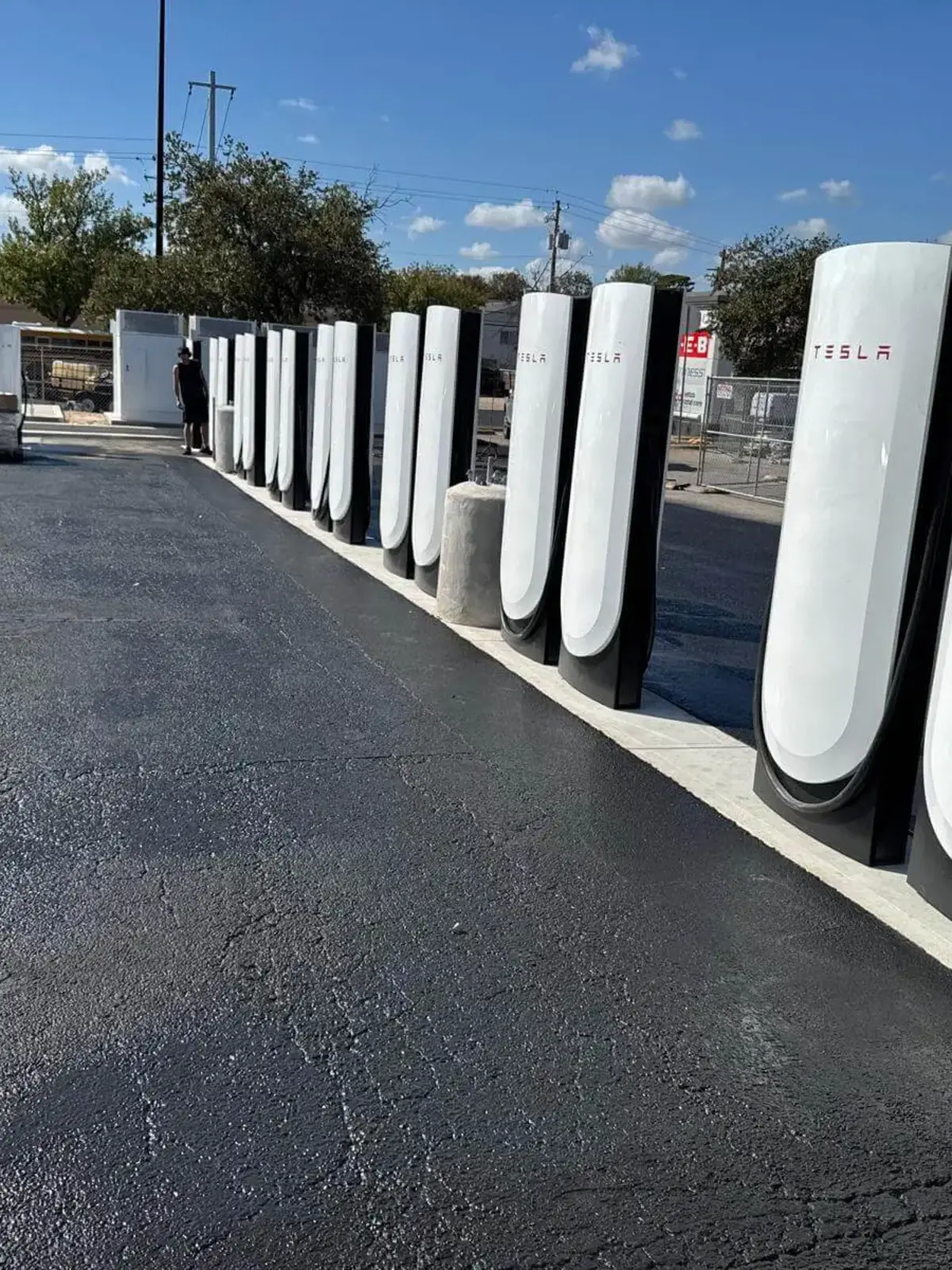 Completed Tesla Supercharger station installation featuring fresh asphalt paving and concrete curbs by Soga Underground.